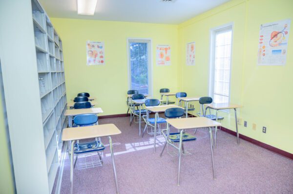 Rows of metal armchairs inside a pale-yellow classroom